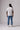 A back image of a male model wearing the PONY White Home jersey and blue jeans standing in a studio.