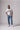An image of a male model wearing the PONY White Home jersey and blue jeans standing in a studio.